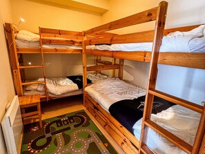 Une chambre avec des lits superposés et un tapis décoré avec un circuit de course.