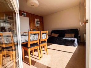 A compact room with a dining table and chairs, a sofa, and a bed.