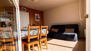 Une pièce de taille modeste comprenant une table et des chaises, un canapé et un lit.