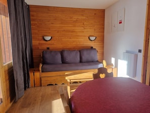 Une pièce chaleureuse avec un mur en bois, un canapé, une petite table et un lit.