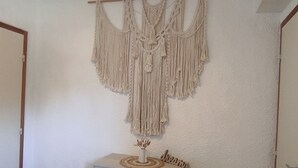 A macrame wall hanging above a dresser with a small vase and the word 'dream' on it. - Cozy F3 apartment near slopes, perfect for families (Besse-et-Saint-Anastaise-Super Besse)