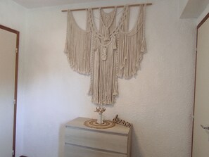 A macrame wall hanging above a dresser with a small vase and the word 'dream' on it.