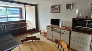 A compact living space with a dining table, a TV, a microwave, and a coffee maker. - Studio cabin 4 pers, center, WIFI (Besse-et-Saint-Anastaise-Super Besse)