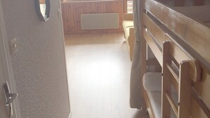 Ein Zimmer mit einem hölzernen Bett, einem Fenster mit Blick ins Freie und einem Heizkörper an der Wand.