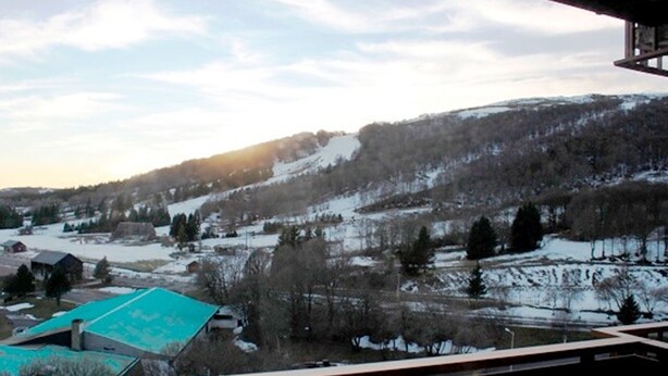 Blick vom Balkon auf eine verschneite Landschaft mit einem Gebäude mit einer grünen Dachbegrünung.
