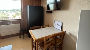Eine kleine Küchenzeile mit Fenster, ein an der Wand befestigter Fernseher und ein gerahmtes Bild.