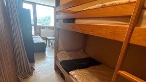 Ein Schlafraum mit Etagenbetten, einem Holzkopfende, einem Schreibtisch und einem Fenster mit Vorhängen.