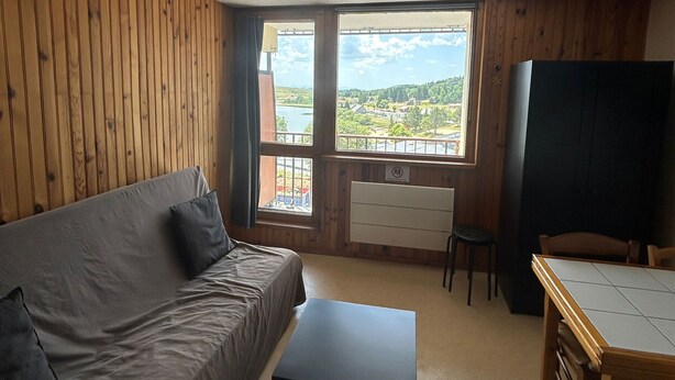Ein Zimmer mit Holzwand, einer Couch, einem kleinen Tisch und einem Fenster mit Landschaftsblick.
