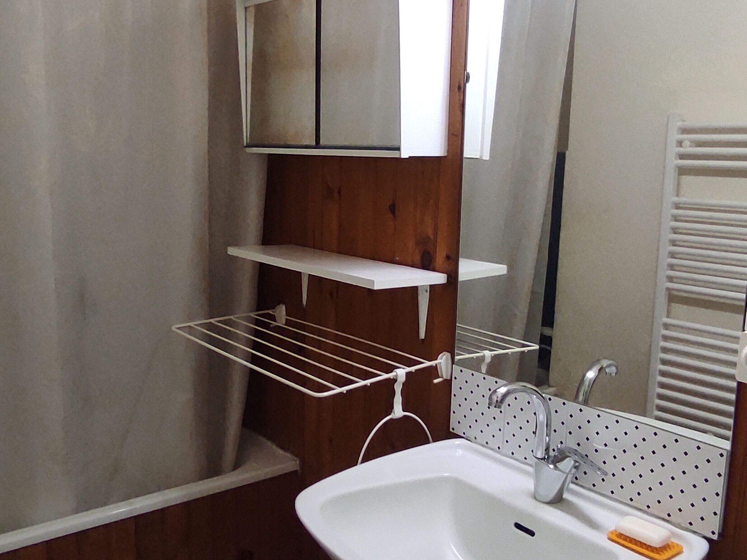Une salle de bain avec un lavabo blanc, un miroir, un porte-serviettes et un meuble en bois.