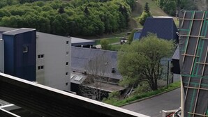 Een woongebied met gebouwen, een weg en een beboste heuvel.