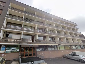 Un hotel de varios pisos con balcones, una entrada a nivel de calle y un estacionamiento.