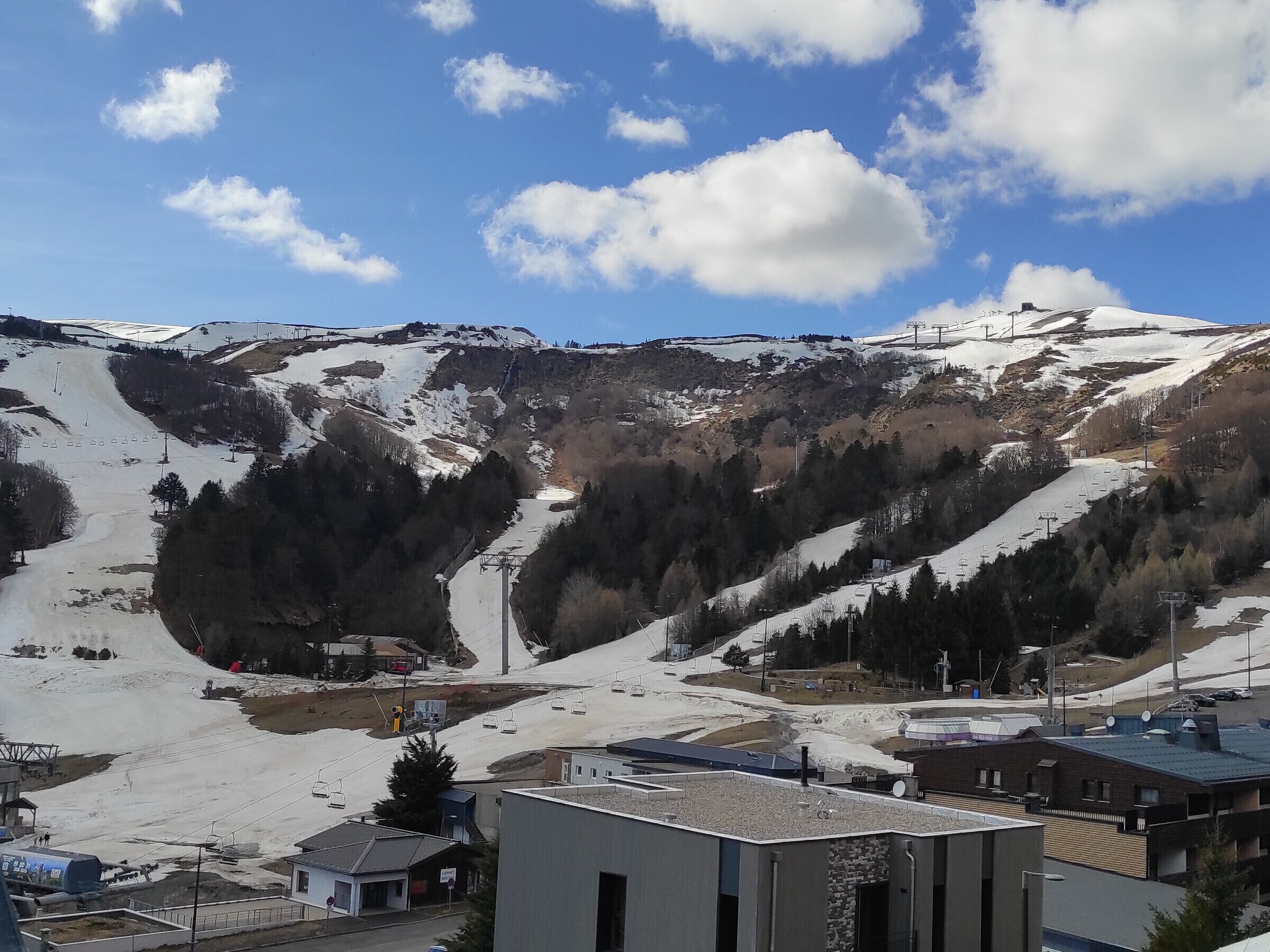 A mountainous landscape with a ski slope, buildings, and a clear sky.