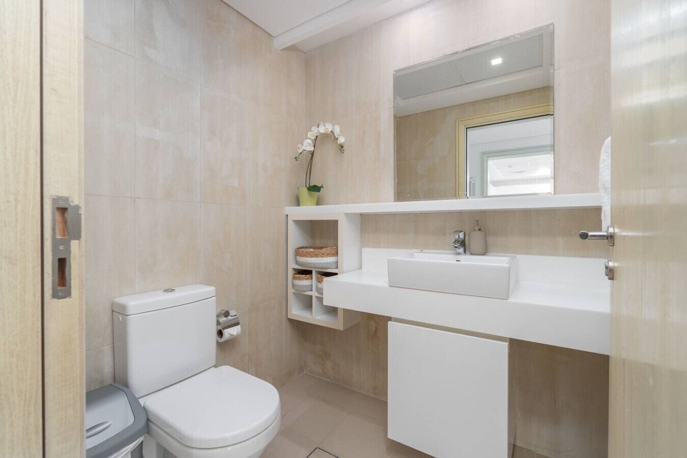 Une salle de bain moderne équipée de toilettes, d’un lavabo et d’étagères de rangement.