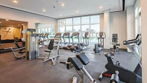 Et moderne fitnesscenter med forskellig træningsudstyr, store vinduer og udsigt til det fri.