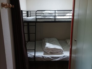 Une chambre avec un lit superposé, une porte en bois et un rideau.
