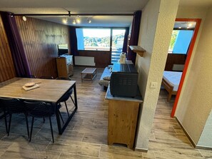 Un espacio habitable compacto con zona de comedor, kitchenette y vistas al exterior.