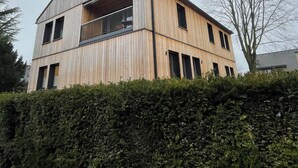Ein modernes, zweistöckiges Gebäude mit geneigtem Dach und einem Balkon im oberen Geschoss.