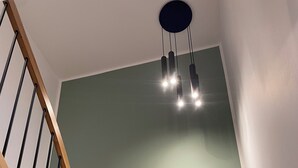 Eine Holztreppe mit einer modernen Leuchte darüber.