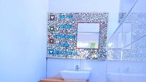 A bathroom with a mosaic wall, a wooden vanity, a sink, and a mirror. - Steps Guest House (Gqeberha (Port Elizabeth))