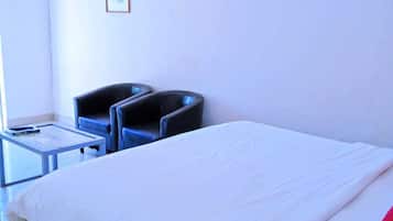 Una habitación de hotel con una cama grande, una mesita pequeña, dos sillas y un cuadro enmarcado en la pared.