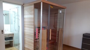 Una habitación con armario de madera, cabina de ducha de vidrio y suelo de madera.