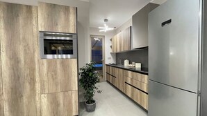 Cuina moderna amb armaris de fusta, electrodomèstics d'acer inoxidable i una planta en test.