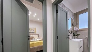 Habitació d'hotel amb llit, bany amb rentapans i mirall, i vista del cel a través d'una finestra.