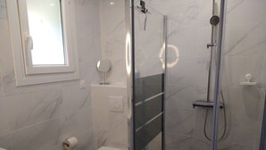 A modern bathroom with a toilet, a shower, and a sink.