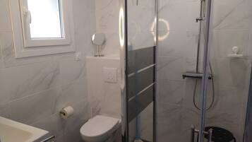 Een moderne badkamer met toilet, douche en wastafel.