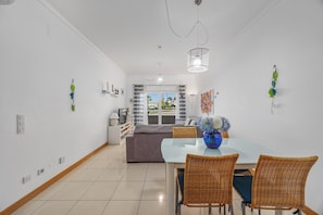 Een moderne woonkamer met een eethoek, een televisie en uitzicht op de omgeving.