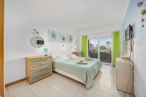 Une chambre Ă coucher comprenant un lit, une commode, des Ćuvres dâart et un balcon avec vue.