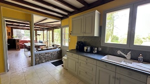A kitchen with stone walls, a large window, and a dining area with a table and chairs.