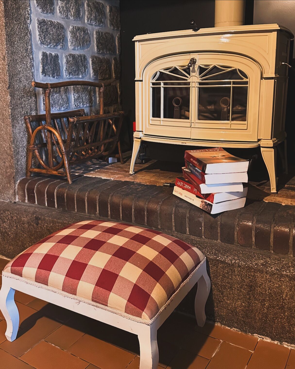 A cozy room with a checkered ottoman, a wooden rocking chair, and a vintage stove.