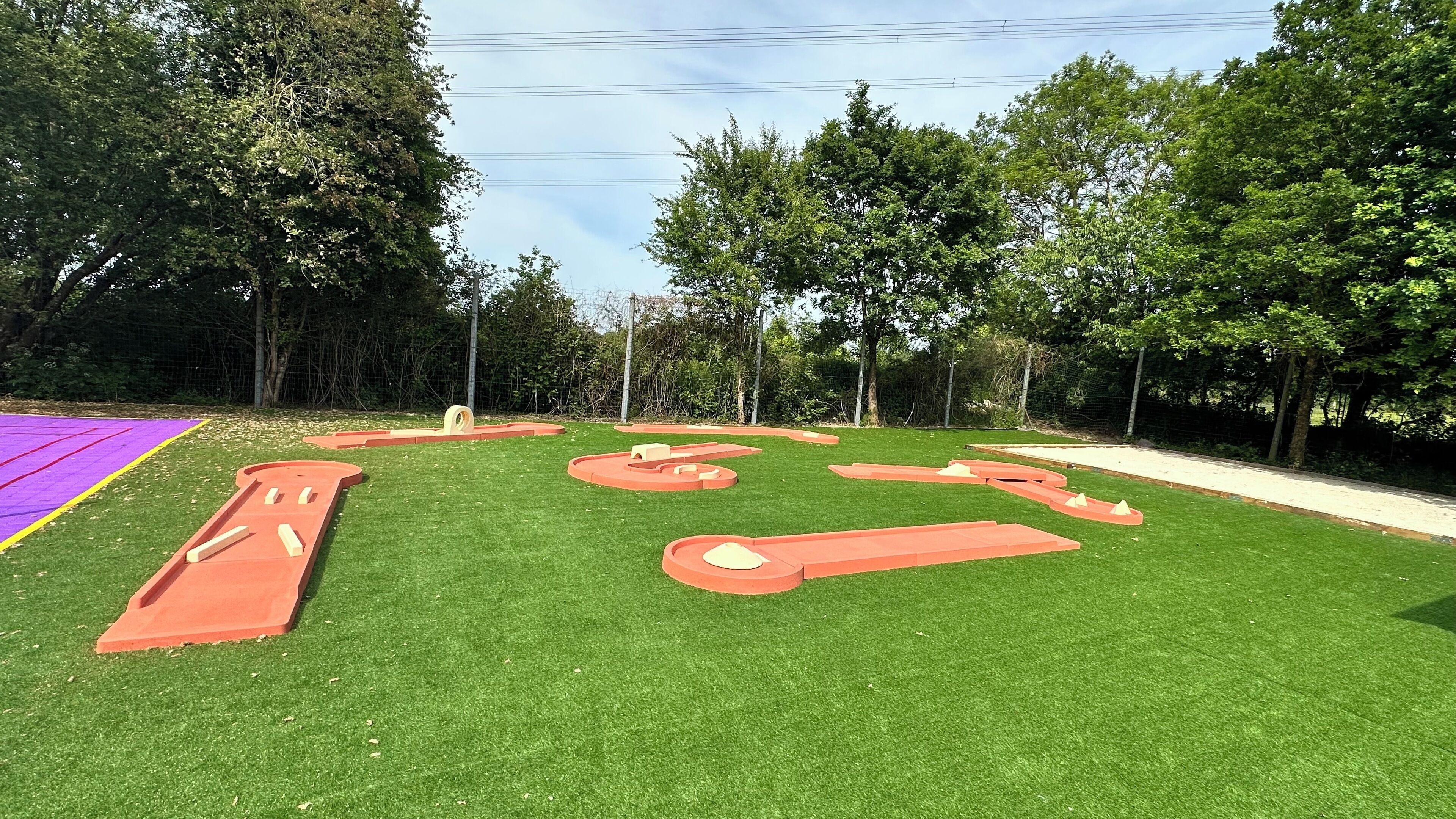 Ein Spielplatz mit Kunstrasen und verschiedenen Spielgeräten.