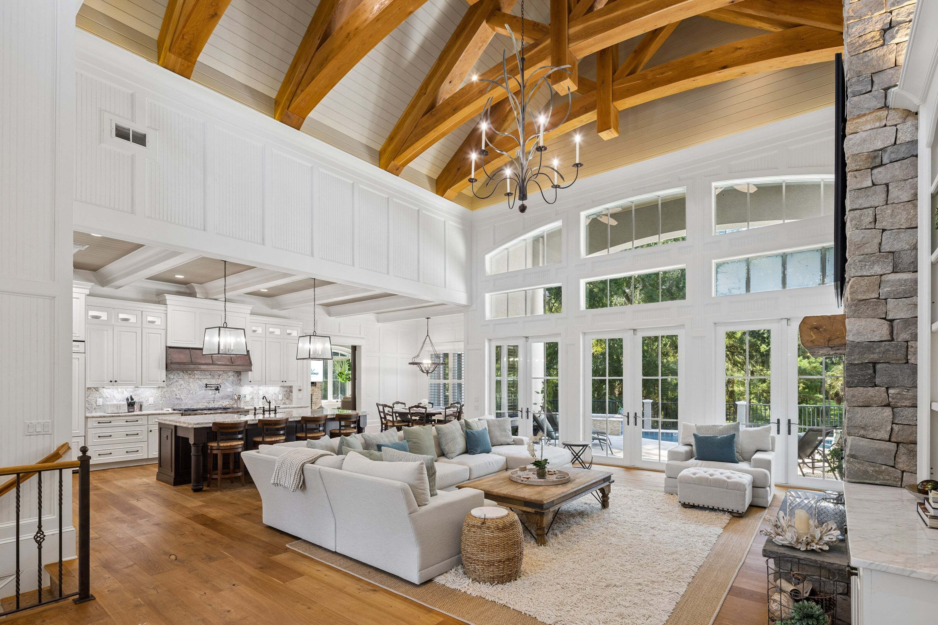 A spacious living area with a high ceiling, wooden beams, and large windows.