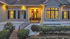 A two-story house with a front porch, a staircase, and a well-maintained garden. - Relaxing Golf Course Getaway in Palmetto Dunes with Private Pool, Spa, and Outdoor Kitchen (Hilton Head Island)