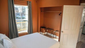 A bedroom with a bed, a window with curtains, a drying rack, and a door to a bathroom. - Funky & Fun! 1BR Apartment, Ground Floor (Baton Rouge)