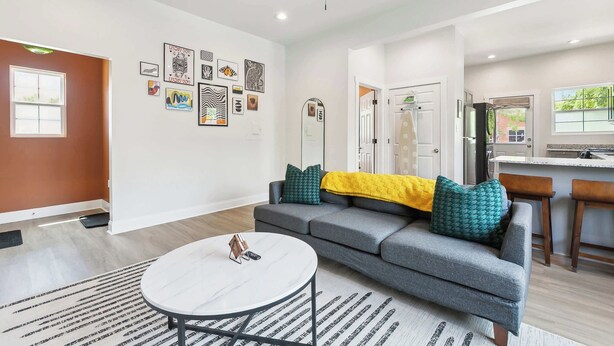 A modern living room with a grey sofa, a round coffee table, and a kitchen in the background. - Funky & Fun! 1BR Apartment, Ground Floor (Baton Rouge)