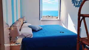 A bedroom with a bed, a window with a view of the sea, and a chair. - Charming sea view apartment for families, with sky tv (Riomaggiore)