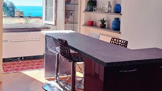 A modern kitchen with a dining area, a glass-fronted cabinet, and a view of the sea. - Charming sea view apartment for families, with sky tv (Riomaggiore)
