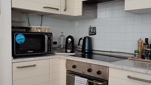 A modern kitchen with white cabinetry, a microwave, a kettle, and an oven. - Charming sea view apartment for families, with sky tv (Riomaggiore)