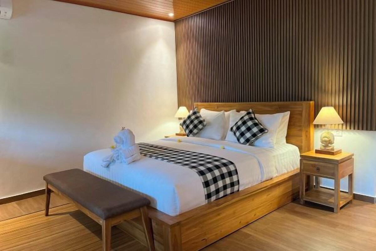 A neatly made bed with a checkered blanket, a wooden headboard, and two bedside lamps.