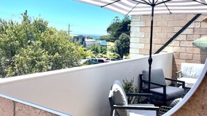 A round mirror reflecting a patio area with outdoor furniture and a view of the surrounding landscape.