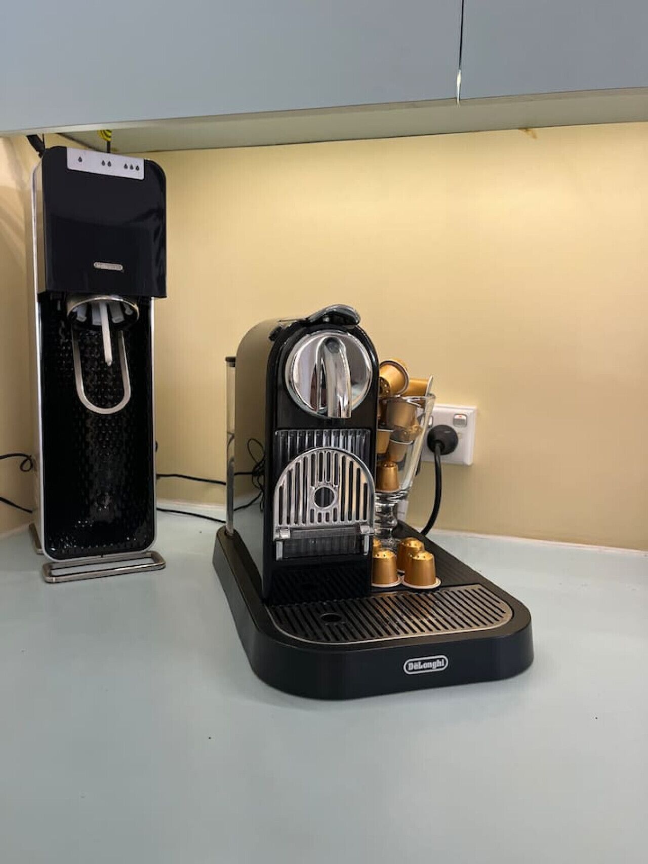En kaffemaskin med en vattenbehållare och en droppuppsamlare placerad på en bänkskiva.