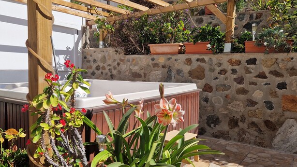 A hot tub under a wooden pergola with potted plants and a stone wall in the background. - Vacation apartment with panoramic views at Finca Gran Calma - ideal for hikers (Santa Lucía de Tirajana)