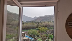 A room with a large window offering a view of a mountainous landscape. - Vacation apartment with panoramic views at Finca Gran Calma - ideal for hikers (Santa Lucía de Tirajana)