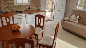 A modern kitchen with a stone backsplash, wooden cabinets, and a dining area with a table and chairs. - Vacation apartment with panoramic views at Finca Gran Calma - ideal for hikers (Santa Lucía de Tirajana)