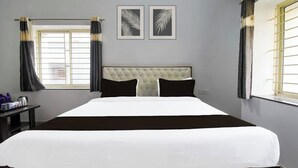 A hotel room with a large bed, two framed leaf artworks on the wall, and a window with curtains. - Hotel Crystal INN (Bhubaneshwar)