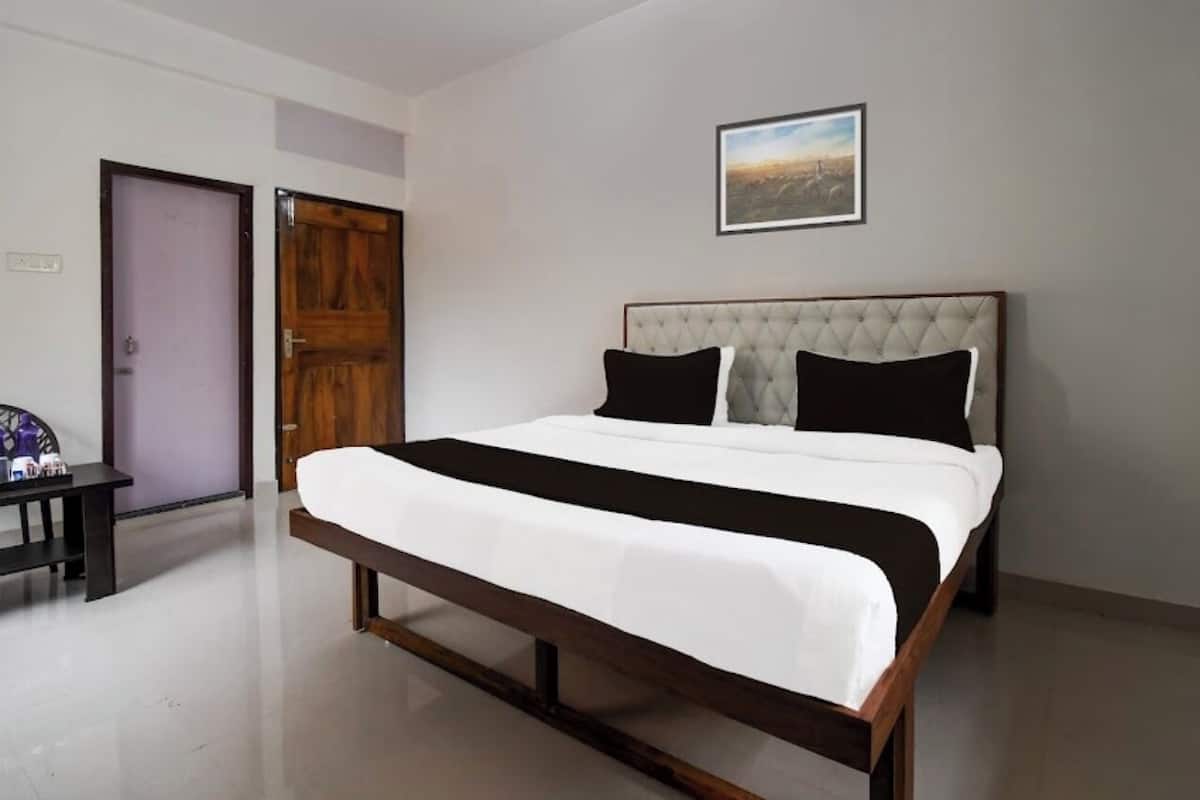 A bedroom with a bed, a wooden door, a bench, and a framed picture on the wall.