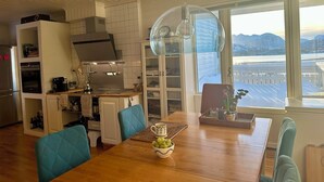 Eine moderne Küche mit weißen Schränken, einem eingebauten Ofen und einem Essbereich mit Holztisch und blauen Stühlen.